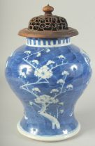 A LARGE CHINESE BLUE AND WHITE PORCELAIN PRUNUS JAR, with carved and pierced hardwood cover, jar
