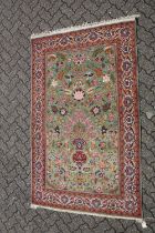 A FINE EARLY 20TH CENTURY PERSIAN KASHAN SIGNED RUG, with foliate decoration on green ground, the