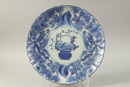 A JAPANESE ARITA PORCELAIN SCALLOP-RIM CHARGER, with central basket of flora and further