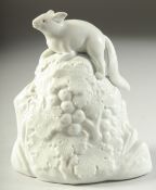 A JAPANESE HIRADO PORCELAIN SQUIRREL, atop a rocky mound with berries and foliage, 14.5cm high.