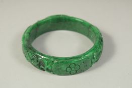 A CHINESE CARVED JADE OR JADEITE BANGLE.