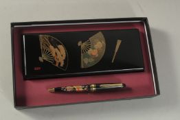 A JAPANESE GILT AND BLACK LACQUER BOX AND PEN SET, boxed.