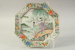 A JAPANESE ROSE PORCELAIN OCTAGONAL PLATE, painted with two ladies on a bridge over water, the