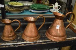 A graduated set of three copper jugs.