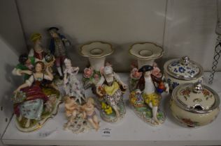 A collection of decorative Dresden figurines and a pair of candlesticks.