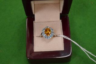 A 9ct white gold dress ring set with a central orange coloured stone, size N.