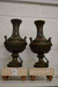 A good pair of classical style metal urns on marble bases.