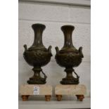 A good pair of classical style metal urns on marble bases.