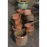 A large quantity of terracotta plant pots together with a large pot with artificial tree.