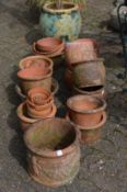 A large quantity of terracotta plant pots together with a large pot with artificial tree.