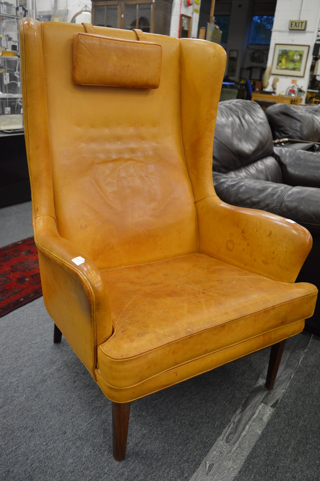 A stylish tan leather upholstered wing armchair.