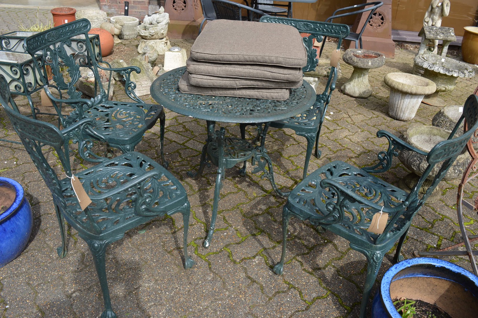 A green painted aluminium patio set comprising circular table and four armchairs.
