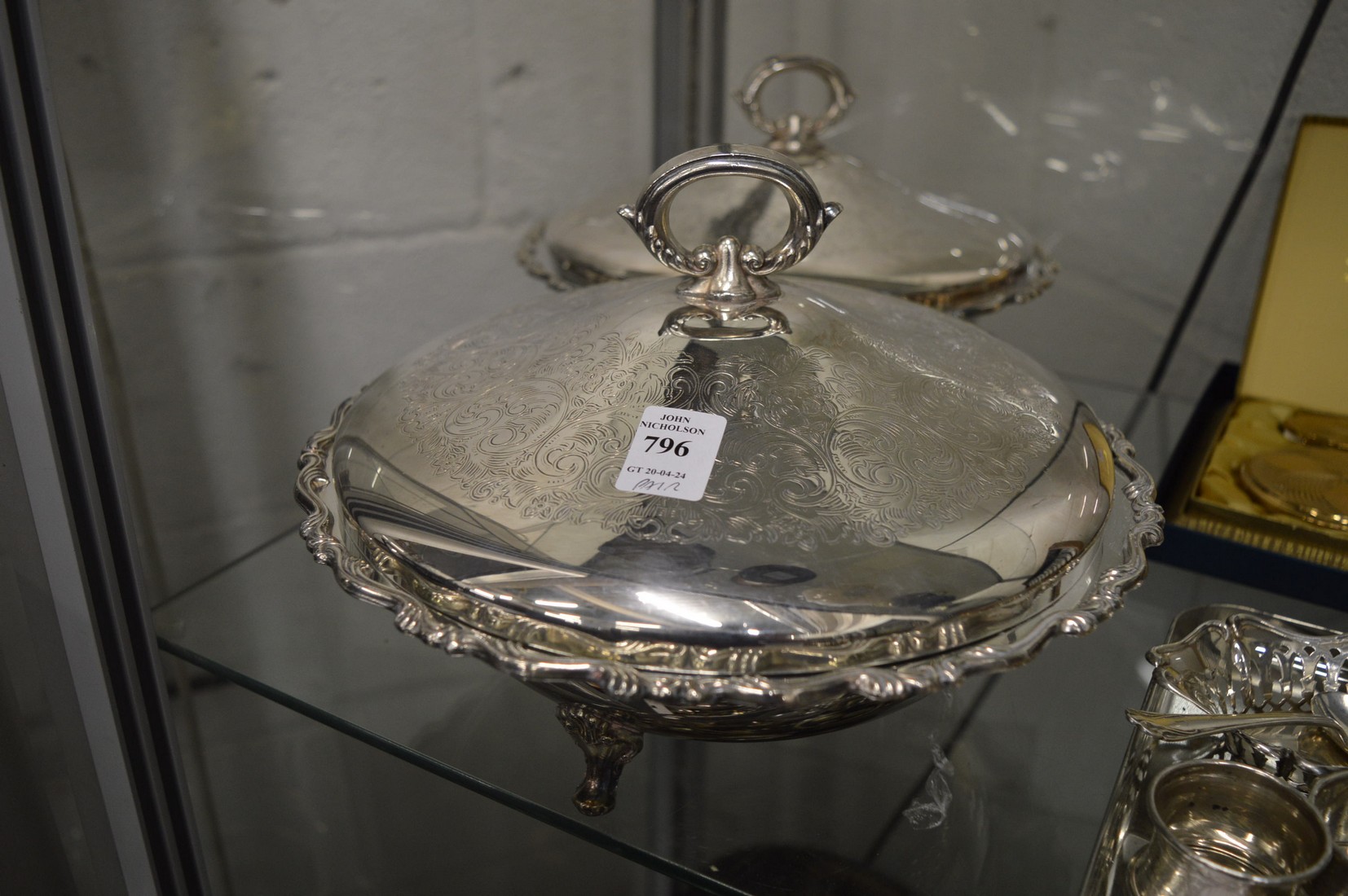 A pair of plated vegetable dishes and covers.