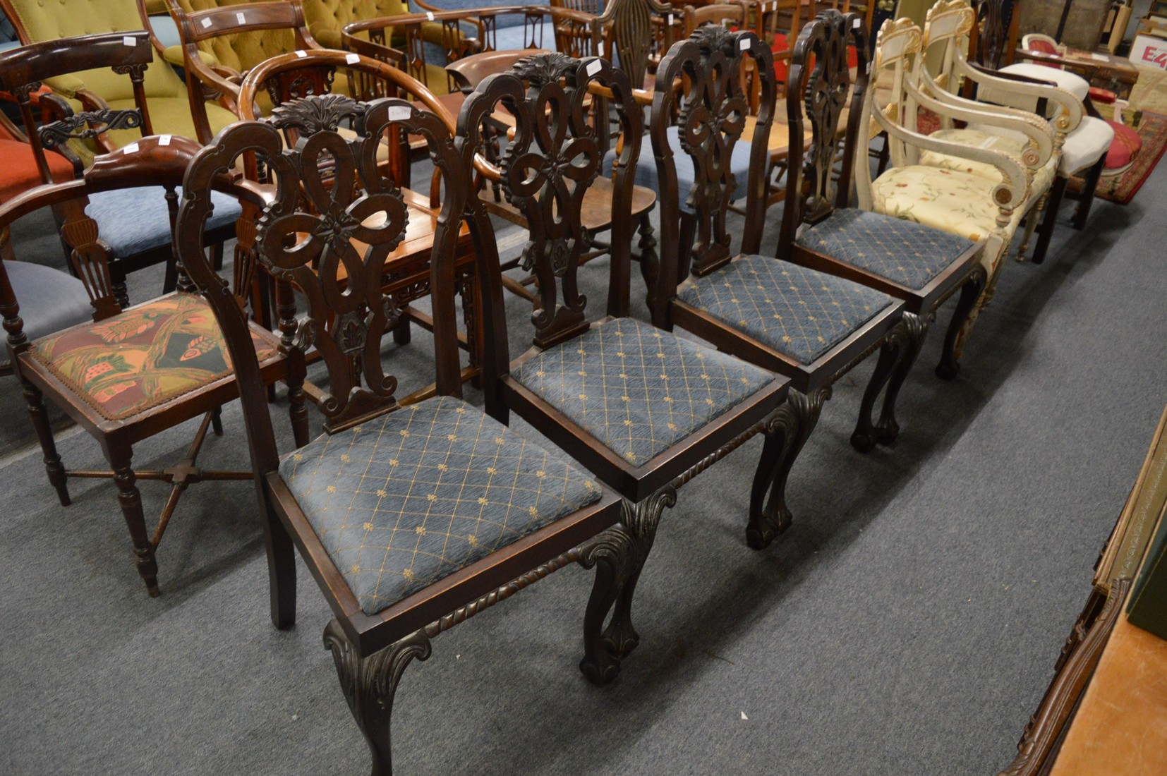 A set of four mahogany dining chairs with carved backs and legs.