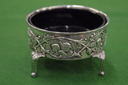 An embossed silver dish with blue glass liner.