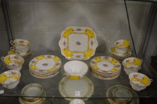 Decorative tea ware with yellow borders and floral sprays.