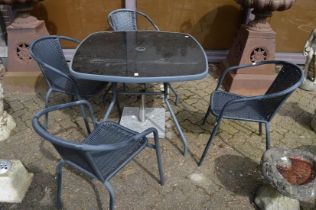 A patio dining set comprising table, four chairs and a parasol base.