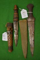 A small African dagger with carved wood sheath and handle together with another dagger.