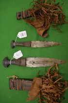 Two African daggers with decorative leather handles and scabbards.