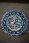 An Iznik style pottery circular dish with pierced border and floral decoration.