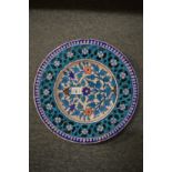 An Iznik style pottery circular dish with pierced border and floral decoration.