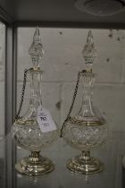 A pair of cut glass scent or oil bottles with white metal mounts.