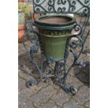 A wrought iron plant pot stand with glazed pot.