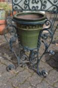 A wrought iron plant pot stand with glazed pot.