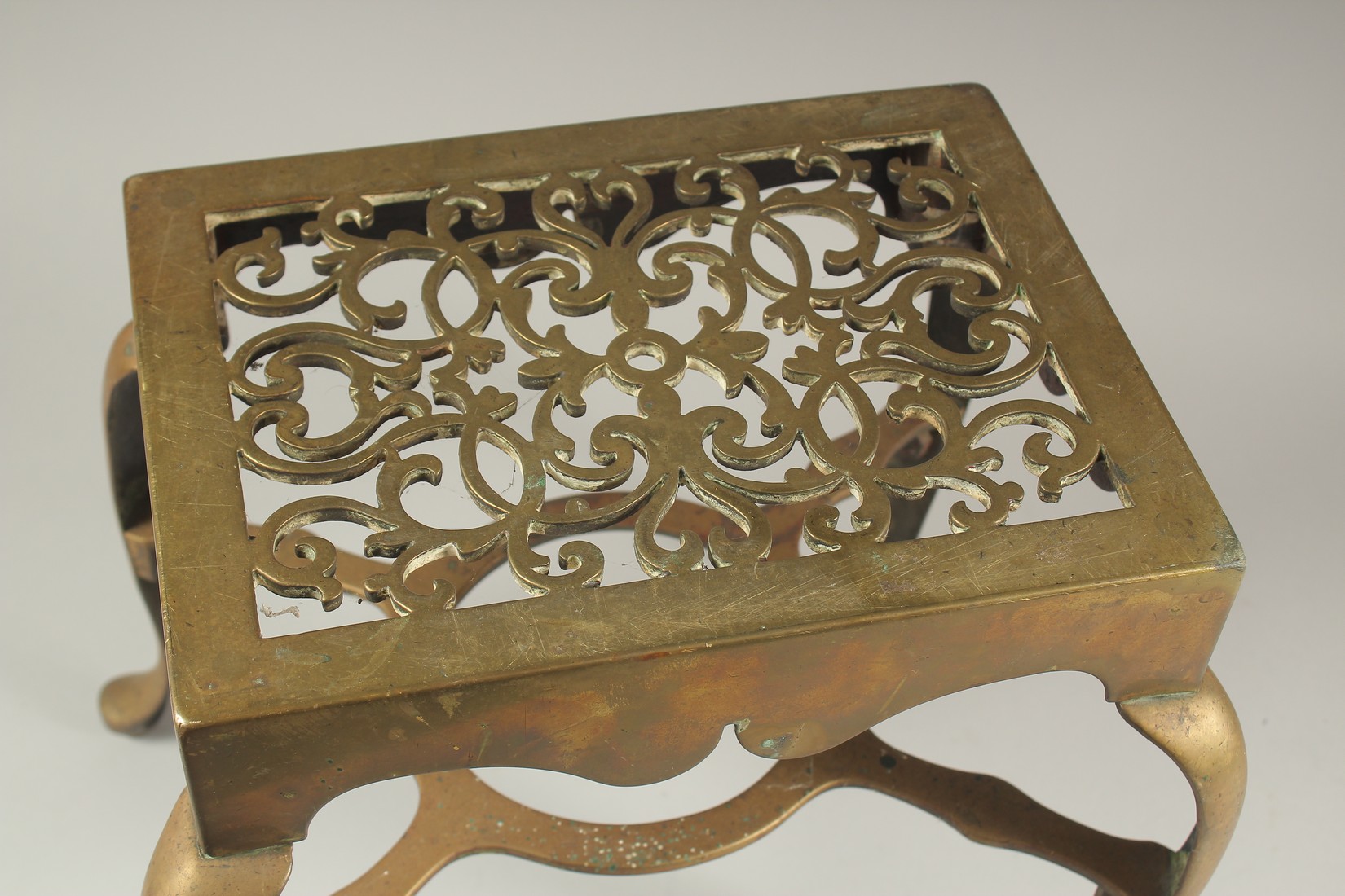 A LARGE BRASS TRIVET with pierced top and four curving legs. 1ft wide x 4ft high. - Image 2 of 3