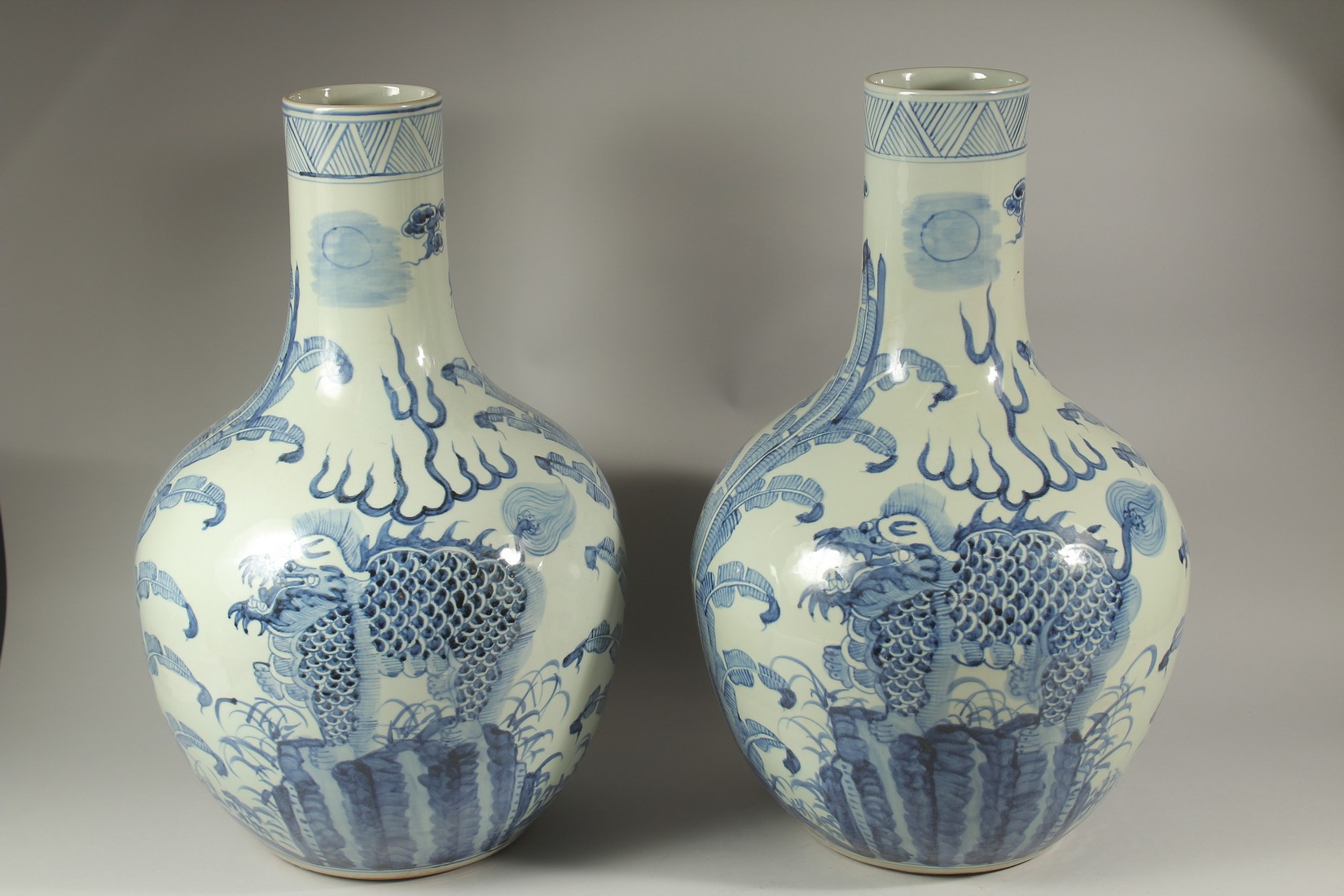 A LARGE PAIR OF CHINESE BLUE AND WHITE BULBOUS VASES decorated with dragons. 60cms high.