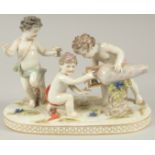 A GOOD PORCELAIN GROUP OF THREE CUPIDS, with a large urn and grapes. 9.5ins long.
