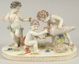 A GOOD PORCELAIN GROUP OF THREE CUPIDS, with a large urn and grapes. 9.5ins long.