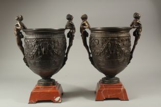 A SUPERB PAIR OF TWO HANDLED CLASSICAL BRONZE URNS on red marble bases. 40cms high.