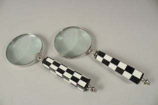 A PAIR OF MAGNIFYING GLASSES with black and white chequered handles.