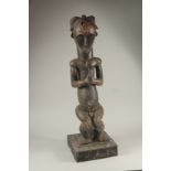 A LARGE CARVED WOOD TRIBAL SEATED FIGURE. 30ins high.