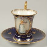 A GOOD DRESDEN CUP AND SAUCER with blue ground, painted with an oval of a lady carrying a tray.