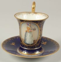 A GOOD DRESDEN CUP AND SAUCER with blue ground, painted with an oval of a lady carrying a tray.