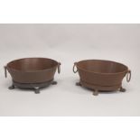 A PAIR OF OVAL IRON PLANTERS with ring handles, on claw feet. 1ft 9ins long.