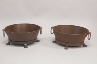 A PAIR OF OVAL IRON PLANTERS with ring handles, on claw feet. 1ft 9ins long.