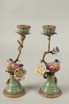 A PAIR OF SEVRES DESIGN PORCELAIN AND GILT METAL BIRD CANDLESTICKS on circular bases. 29cms high.