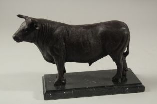 A BRONZE BULL on a marble base. 23cms long.