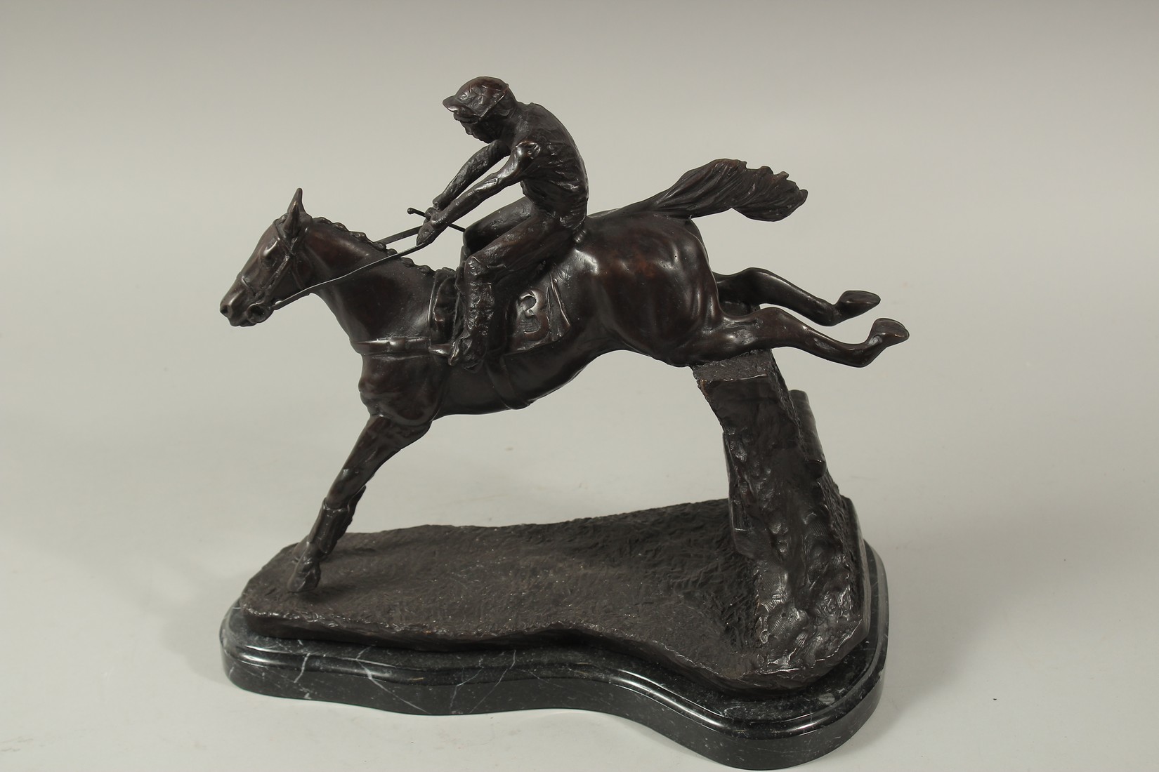 A FINE BRONZE GROUP, HORSE AND JOCKEY OVER THE FENCE, on a marble base. 12ins high.