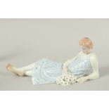 A MEISSEN FIGURE OF A LYING GIRL HOLDING A BUNCH OF FLOWERS. Modelled by Philipp Lane c. 1910. 25cms