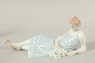 A MEISSEN FIGURE OF A LYING GIRL HOLDING A BUNCH OF FLOWERS. Modelled by Philipp Lane c. 1910. 25cms