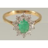 AN 18CT YELLOW AND WHITE GOLD OVAL EMERALD AND RBC DIAMOND CLUSTER RING. Emerald 0.80ct. Diamonds