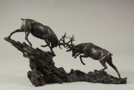 A GOOD PAIR OF BRONZE FIGHTING STAGS on a rustic base. 40cms long.
