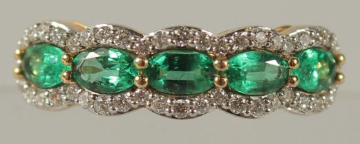 AN 18CT YELLOW GOLD FIVE STONE EMERALD AND DIAMOND HALF HOOP RING.