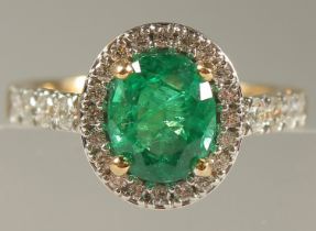 AN 18CT YELLOW GOLD FINE OVAL EMERALD AND DIAMOND CLUSTER RING.
