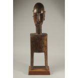 A LARGE TRIBAL CARVED WOOD BUST on a stand. 27ins high.