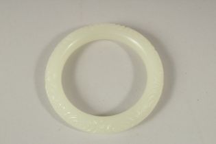 A CHINESE CARVED WHITE BANGLE. 7.5cms diameter.